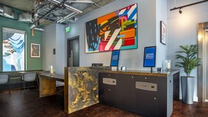 A reception desk with a modern design, a large abstract painting on the wall, and a potted plant. - Hendrick Smithfield (Dublin)