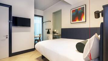 A hotel room with a bed, a TV, a desk, and a chair.