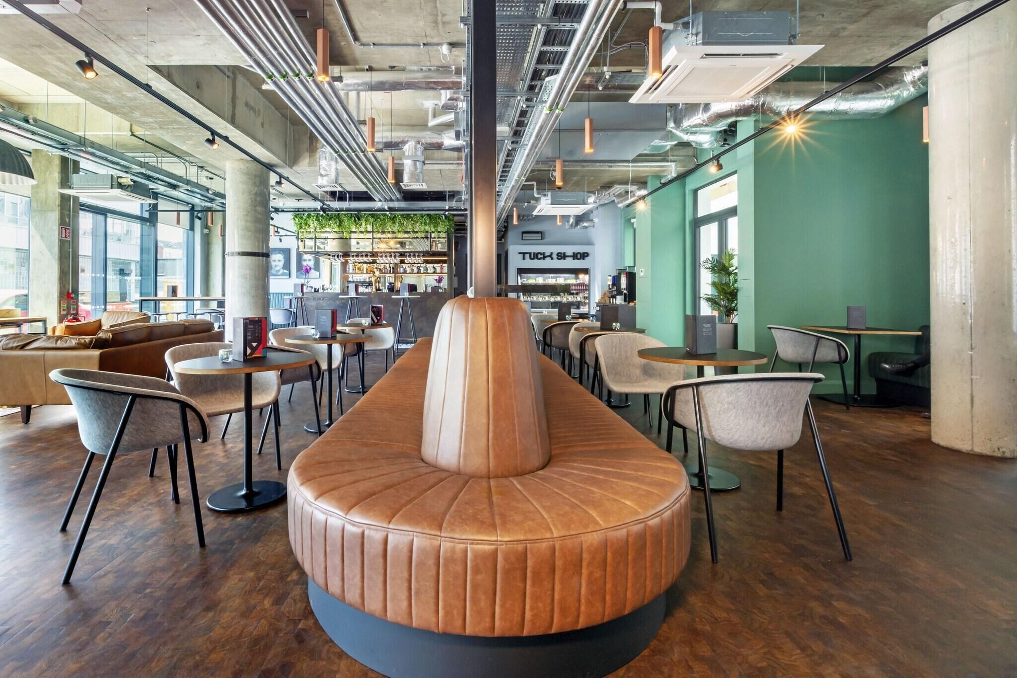 A modern interior with a central seating area, tables, chairs, and a bar area with shelves.