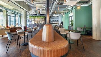 A modern interior with a central seating area, tables, chairs, and a bar area with shelves.