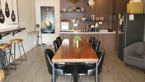 Une cuisine moderne avec une table à manger en bois, des chaises noires et un réfrigérateur.