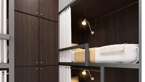 Une chambre avec un lit superposé, une armoire, un rideau et un luminaire.