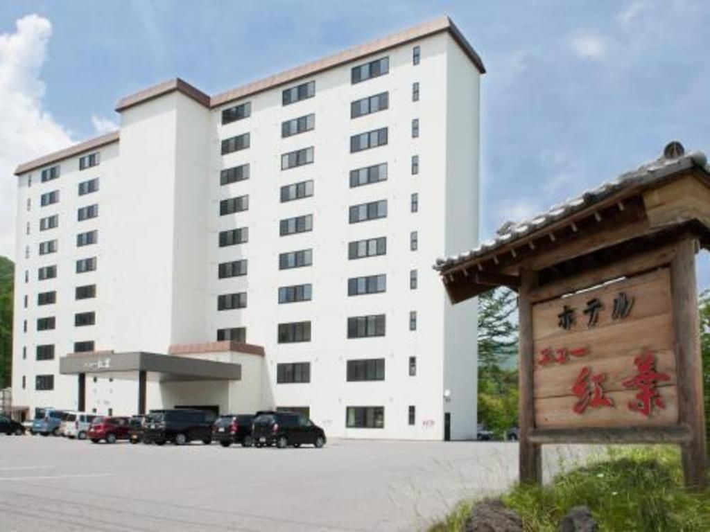 Un edificio de hotel de varios pisos con un estacionamiento al frente.