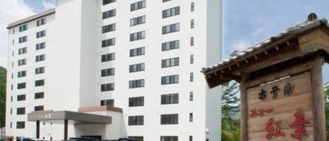 Un edificio de hotel de varios pisos con un estacionamiento al frente.