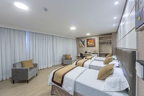 A hotel room with two beds, a desk, a chair, and a wardrobe.