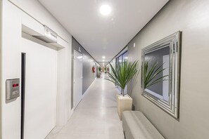 A hotel corridor with a bench, a fire extinguisher, and a sign indicating the direction to the restaurant. - Hotel Global (São Paulo)