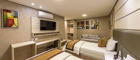 A hotel room with two beds, a TV, a desk, and a wardrobe.