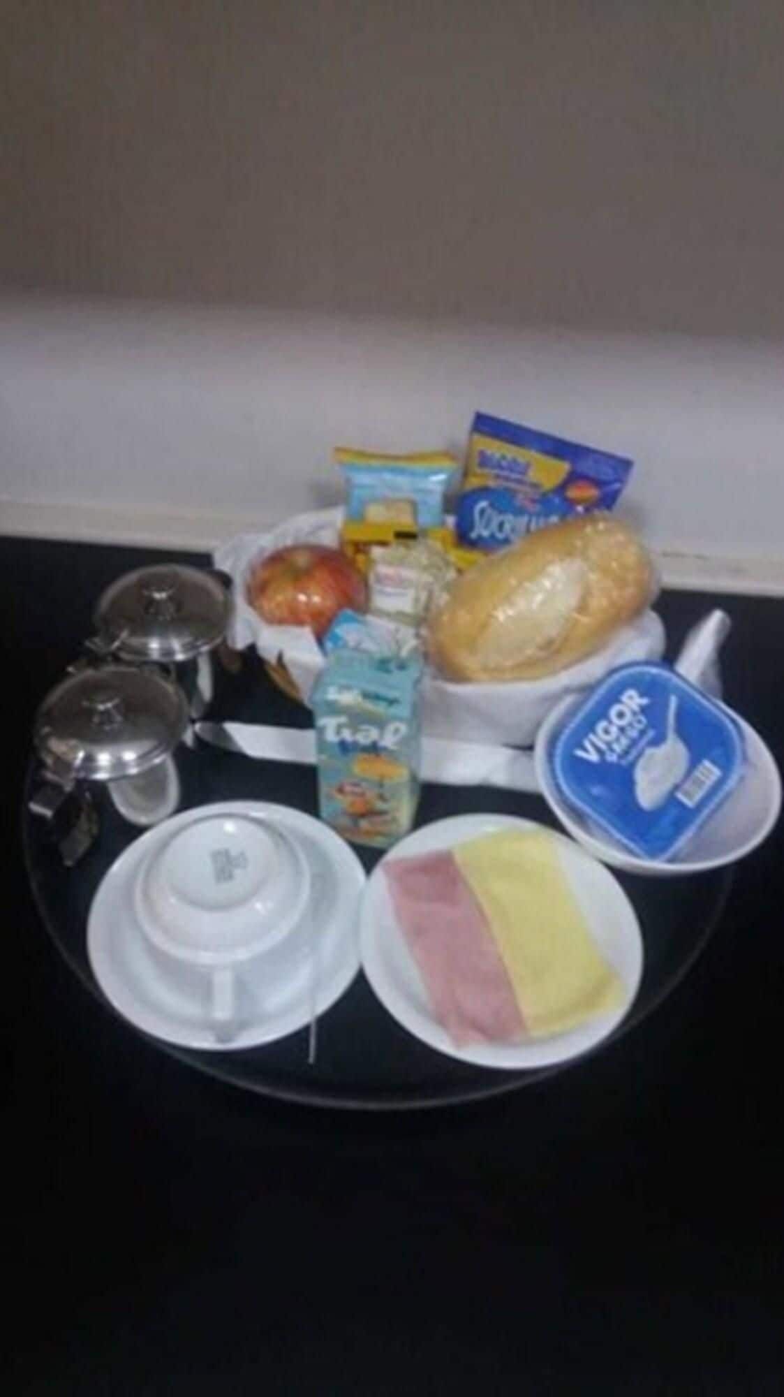 Ein Tablett mit Lebensmitteln, darunter Brot, eine Milchpackung, ein Joghurtbecher und eine Schüssel mit Schinken und Käse.