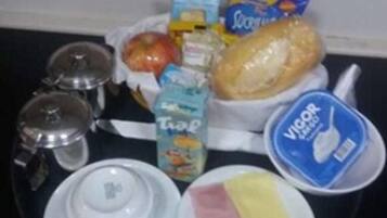 Ein Tablett mit Lebensmitteln, darunter Brot, eine Milchpackung, ein Joghurtbecher und eine Schüssel mit Schinken und Käse.