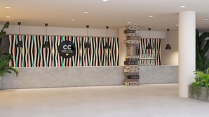 Una hall moderna di un hotel con un design di parete a righe, una colonna centrale e luci a sospensione.