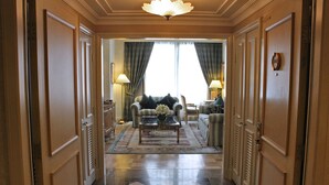 A hallway leading to a living room with a sofa, armchairs, a coffee table, and a chandelier. - The Langham Hotel, Melbourne (Melbourne)