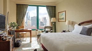 A hotel room with a bed, desk, chair, and a view of city buildings. - The Langham Hotel, Melbourne (Melbourne)