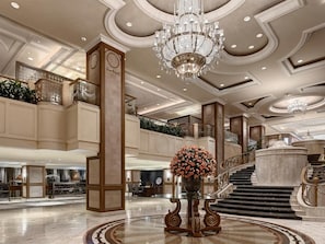 Eine prachtvolle Lobby mit einem Kronleuchter, einer Treppe und einer großen Blumenkomposition.