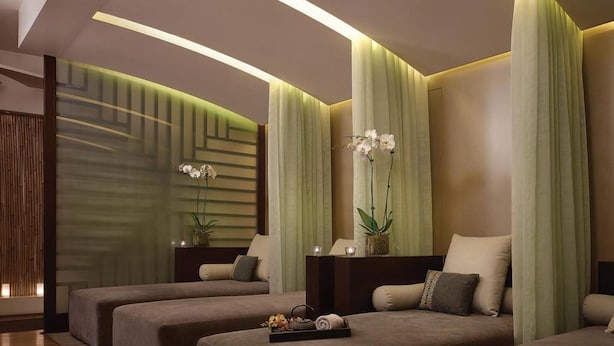 A modern spa room with two massage tables, green ambient lighting, and decorative plants. - The Langham Hotel, Melbourne (Melbourne)