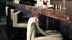A bar area with a marble countertop, bar stools, a vase with flowers, and a glass of red wine. - The Langham Hotel, Melbourne (Melbourne)