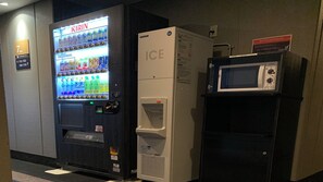 A vending machine with a water dispenser and a microwave on a counter. - Apa Hotel A Namba Minami Ebisucho Ekia (Osaka)