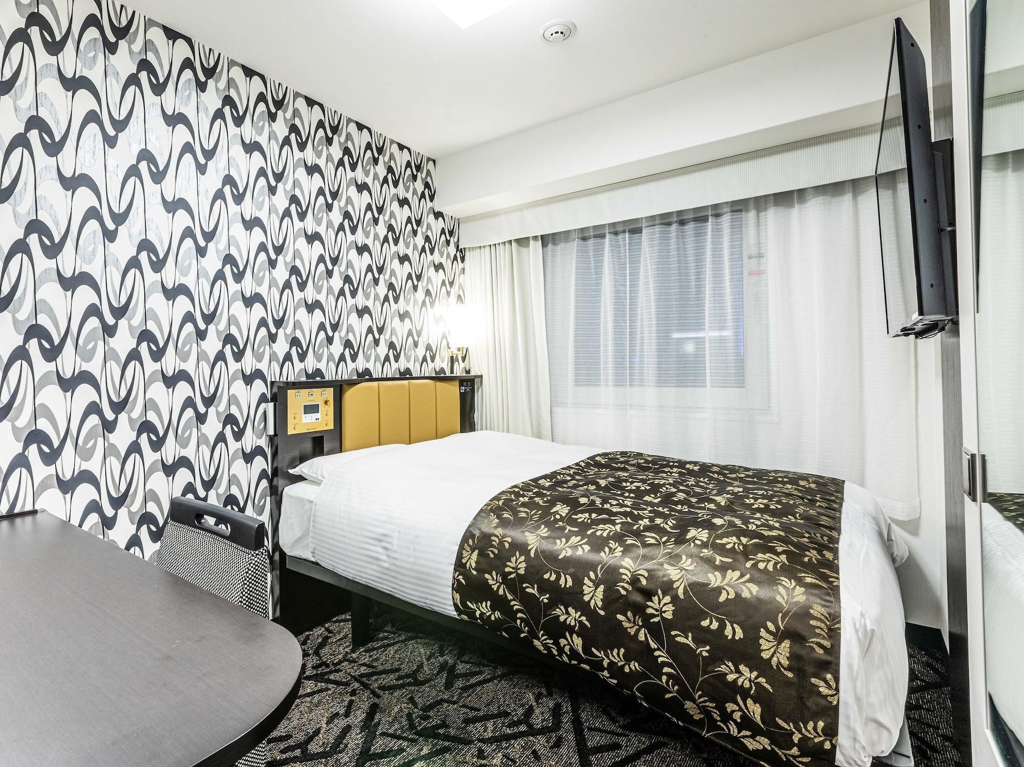 Une chambre d’hôtel équipée d’un lit, d’un bureau, d’une chaise, d’une télévision et d’une fenêtre avec des rideaux.