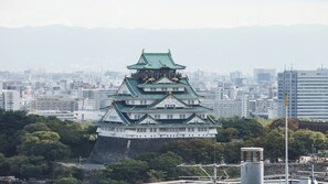 A traditional Japanese castle with multiple tiers and a green roof, surrounded by urban buildings and greenery. - Apa Hotel A Namba Minami Ebisucho Ekia (Osaka)