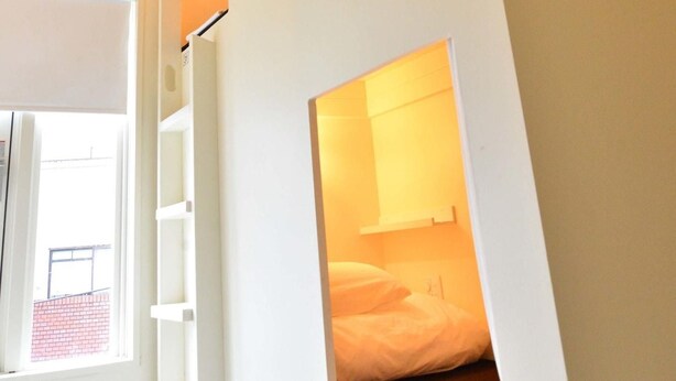 A modern room with a bed, a window, and a light fixture. - Almond Hostel And Cafe (Tokyo)