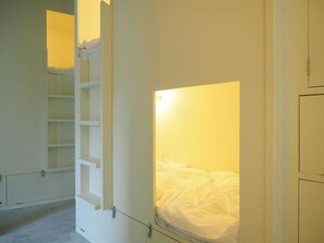 Une chambre avec un lit superposé, une échelle et une étagère.
