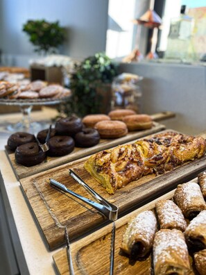 A buffet with various pastries and desserts, including donuts, a pastry with nuts, and a rolled dessert. - Hotel Kivir Sevilla (Seville)