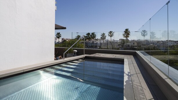 A rooftop pool with a clear view of palm trees and buildings in the background. - Hotel Kivir Sevilla (Seville)