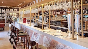 A bar area with a marble counter, wooden chairs, and shelves stocked with bottles and glasses. - Hotel Kivir Sevilla (Seville)