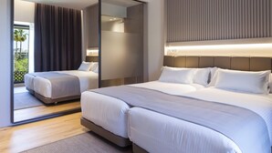 A modern hotel room with two beds, a large mirror, and a view of greenery outside. - Hotel Kivir Sevilla (Seville)