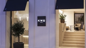 A modern building entrance with a sign reading 'KIVIR SEVILLA,' a potted plant, and a staircase leading to an interior space. - Hotel Kivir Sevilla (Seville)