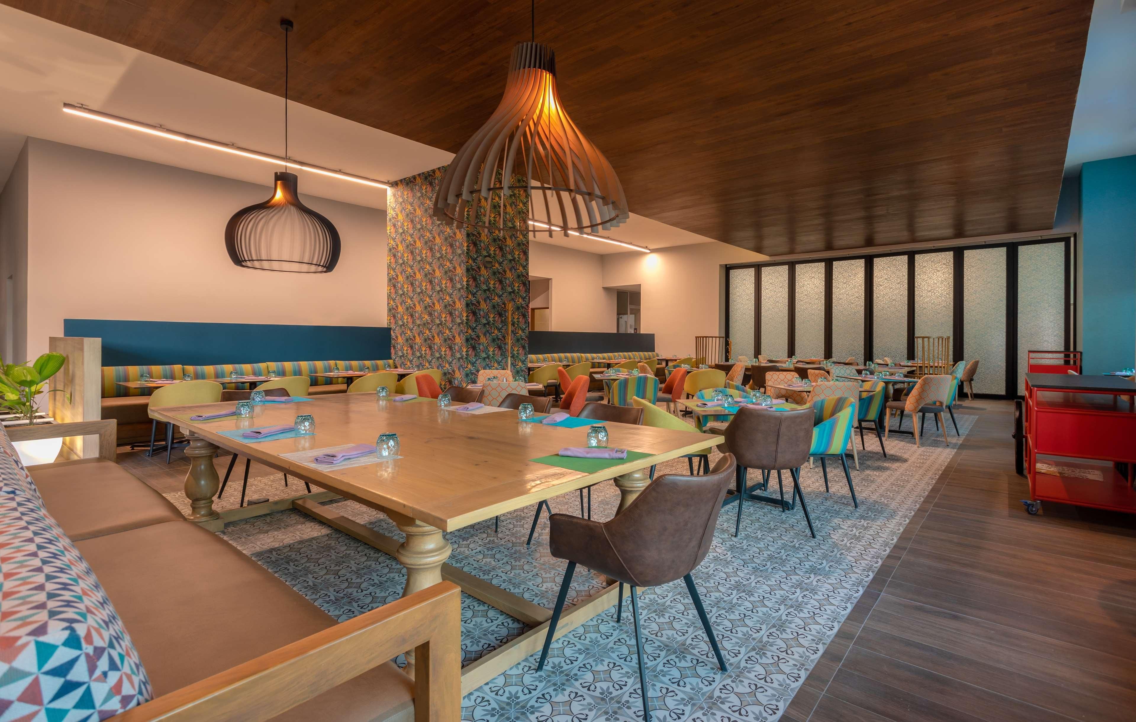 Un'elegante zona pranzo moderna con un grande tavolo di legno, diverse sedie e un lampadario originale.