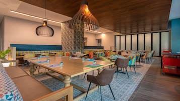 Un'elegante zona pranzo moderna con un grande tavolo di legno, diverse sedie e un lampadario originale.