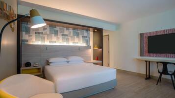 Quarto de hotel moderno com uma cama grande, mesas de cabeceira, uma escrivaninha e uma cadeira.