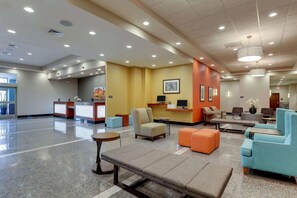 A hotel lobby with a reception desk, seating area, and a large window. - Drury Inn Suites Phoenix Chandler Fashion Center (Phoenix)