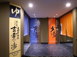 Un couloir avec des panneaux indicateurs menant au Grand Spa « Genyo » et un sol carrelé.