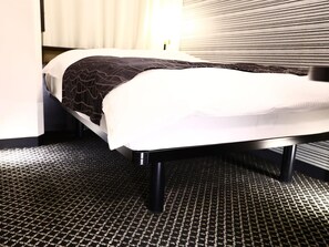 A hotel room with a bed, a patterned carpet, and a window with blinds. - Apa Hotel Yamanote Otsukaeki Tower (Tokyo)