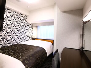 Habitación de hotel con cama, escritorio, silla, ventana con cortinas y pared con diseño.