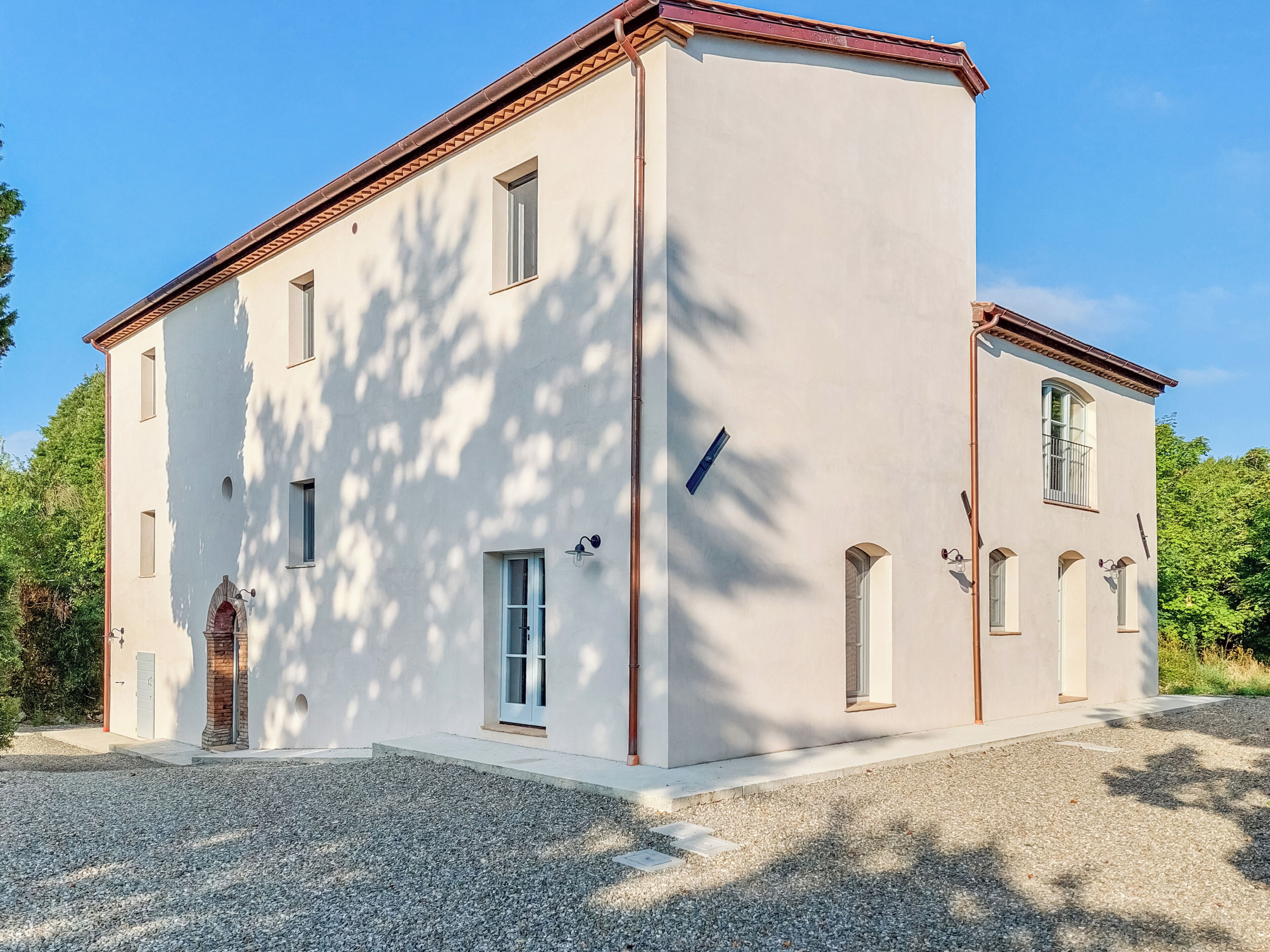 A two-story building with a symmetrical facade, multiple windows, and a gravel driveway.