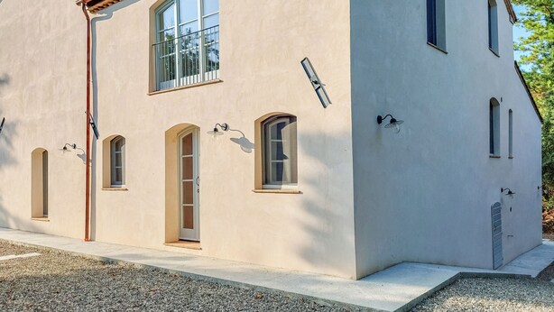 Een gebouw met twee verdiepingen, een beige gevel, veel ramen en een pannendak.
