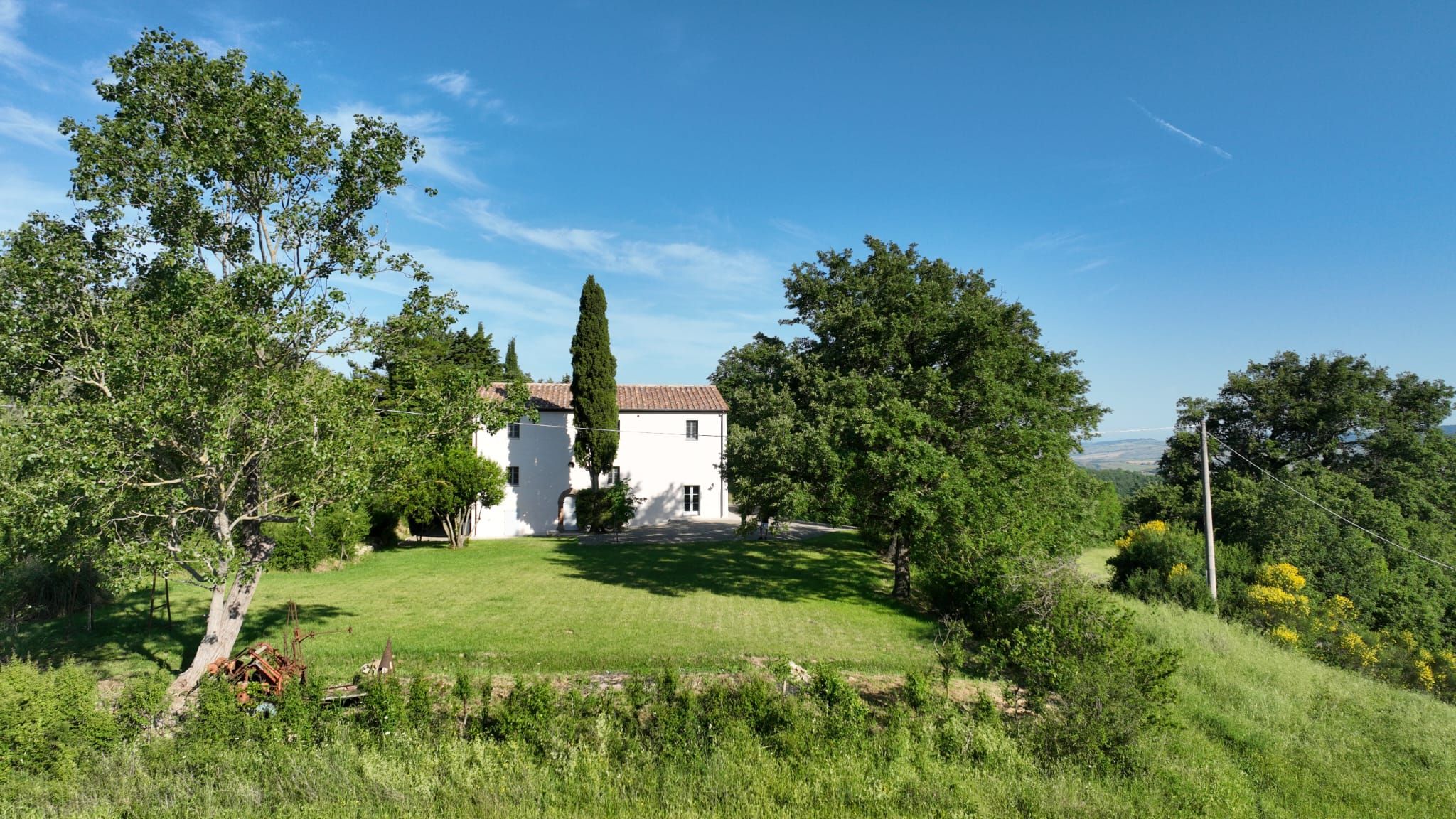 A white building with a tiled roof, surrounded by lush greenery and trees.