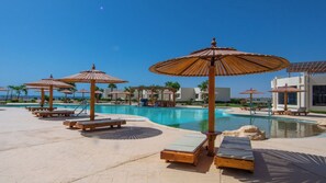 A pool area with sun loungers and umbrellas, surrounded by buildings. - New Eagles Resort & Aqua Park (Hurghada)