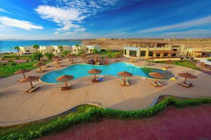 A resort with a large swimming pool, sun loungers, umbrellas, and a view of the sea. - New Eagles Resort & Aqua Park (Hurghada)