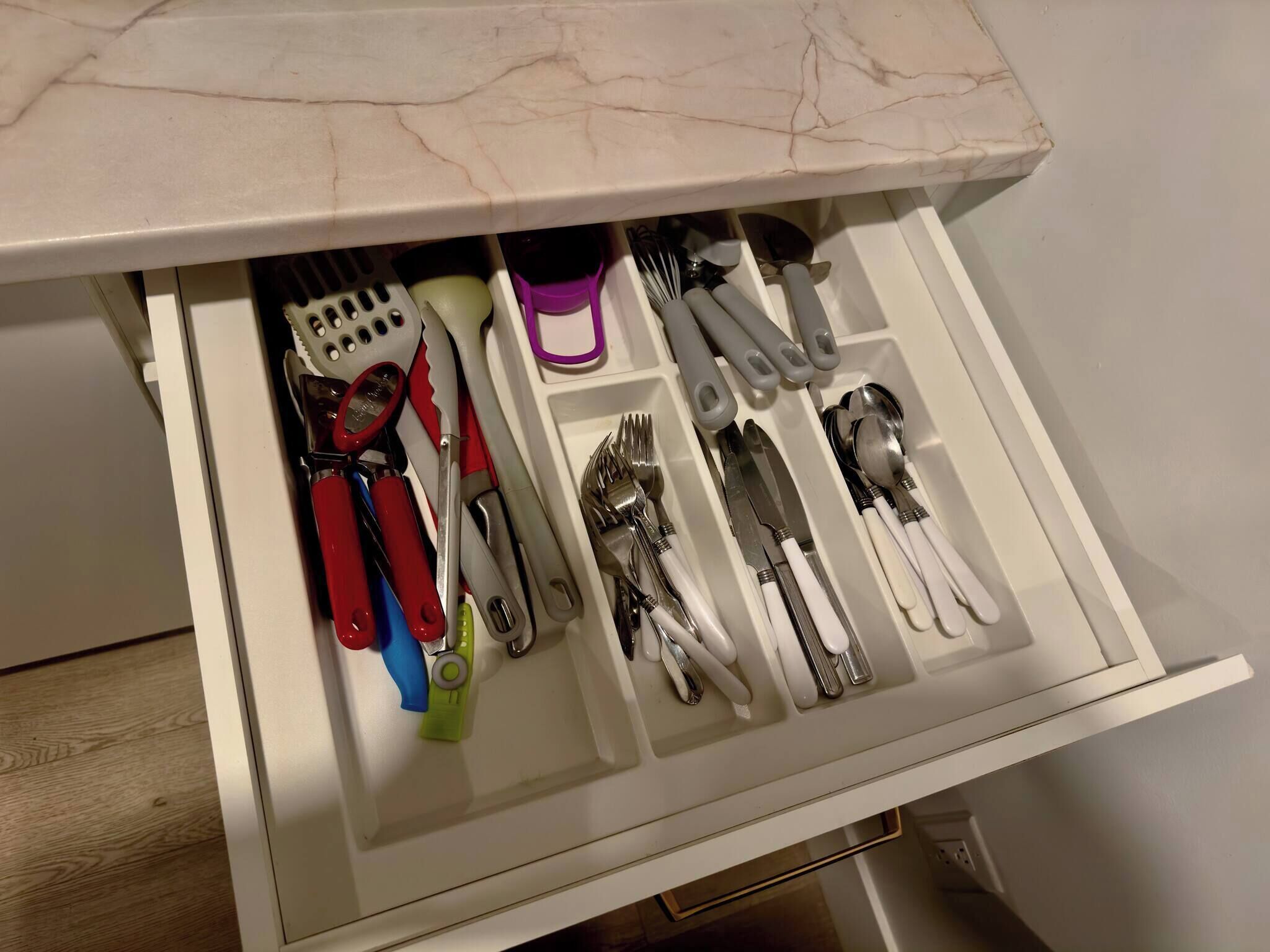 Un cajón con utensilios y herramientas de cocina ordenados en compartimentos.