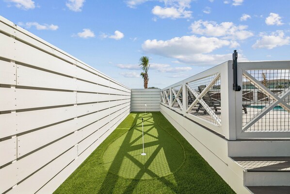 Terraço com grama sintética, uma palmeira e uma piscina.