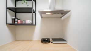 Cozinha com bancada de madeira, uma prateleira preta com objetos e um exaustor de aço inoxidável, e um laptop.