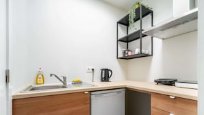 Uma cozinha moderna com lava-louças, cafeteira e um armário com uma planta.