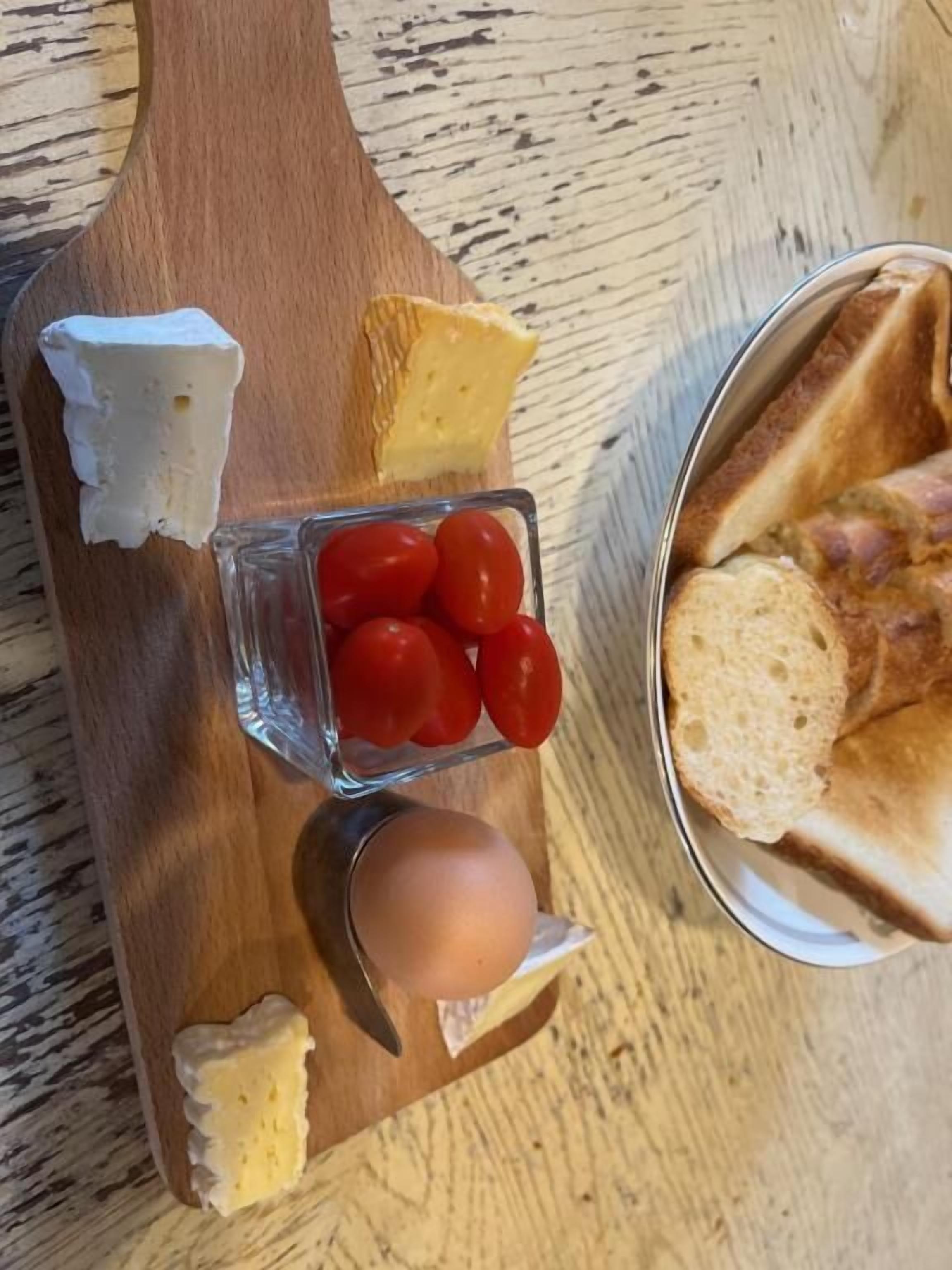Una tabla de madera con queso, tomates y pan.