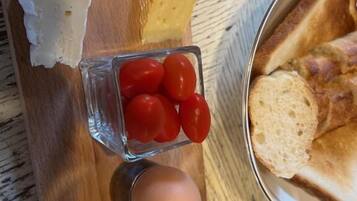 Una tabla de madera con queso, tomates y pan.