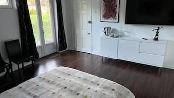 A bedroom with a bed, a TV, a white dresser, and a chair.