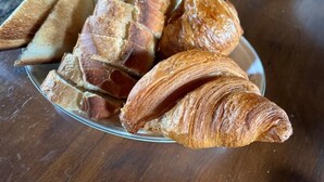 A plate with bread and a croissant.