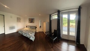 A bedroom with a bed, a chair, a desk, and a large window with curtains.